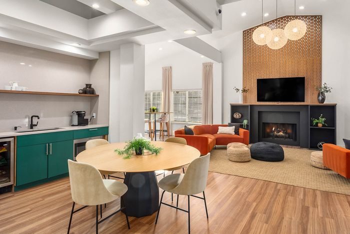 Inviting living space with modern decor, featuring a cozy fireplace, vibrant orange sofas, and a sleek kitchen area.