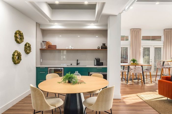 Chic modern dining area with elegant round table, stylish chairs, and vibrant greenery, complemented by a sleek kitchen and natural light from large windows.