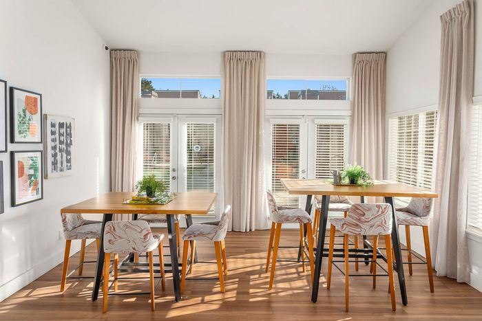 Bright dining area with modern decor, featuring sleek wooden tables, stylish chairs, and expansive windows for natural light.