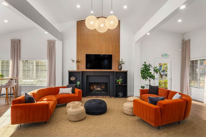 Elegant living room featuring vibrant orange sofas, cozy fireplace, and modern decor with ample natural light.