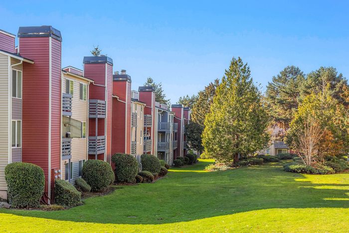 Charming apartment complex with vibrant exterior, surrounded by lush greenery and peaceful landscaping.