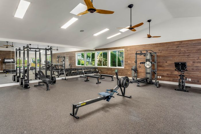 Bright and modern fitness studio featuring top-tier gym equipment, full-length mirrors, and stylish wood accents.