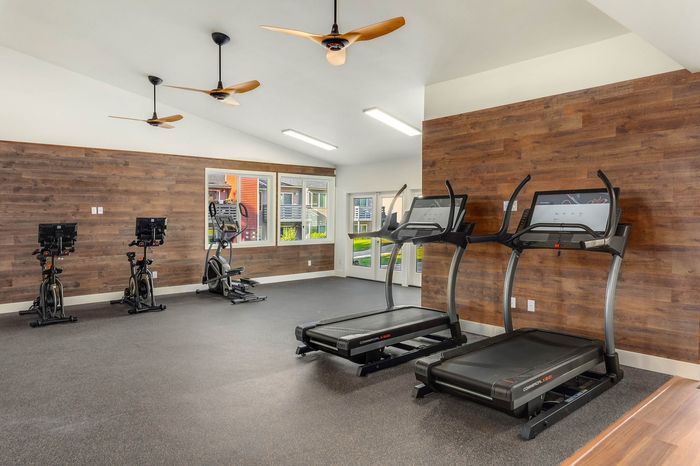 Modern fitness center with state-of-the-art treadmills, exercise bikes, and elegant wood accents.