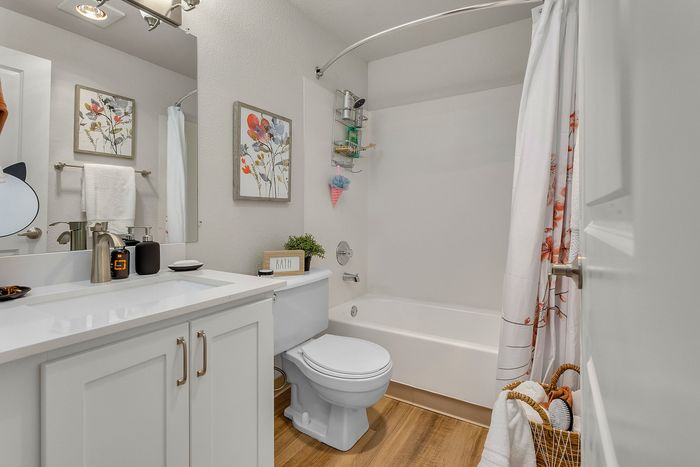 Elegant bathroom showcasing modern fixtures, white cabinetry, and vibrant floral decor, offering a fresh and airy atmosphere.