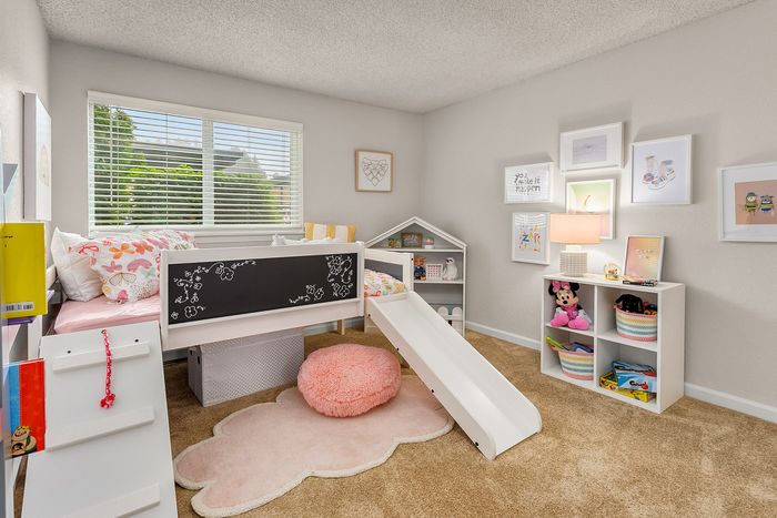 Charming children's bedroom featuring a loft bed with slide, colorful decor, and playful storage solutions.