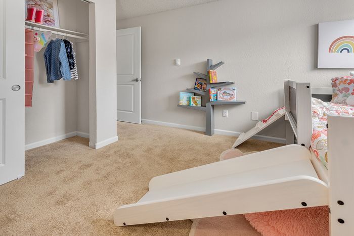 Charming children's room featuring a cozy bed with colorful bedding, a creative tree-like bookshelf, and a fun slide for added playfulness.