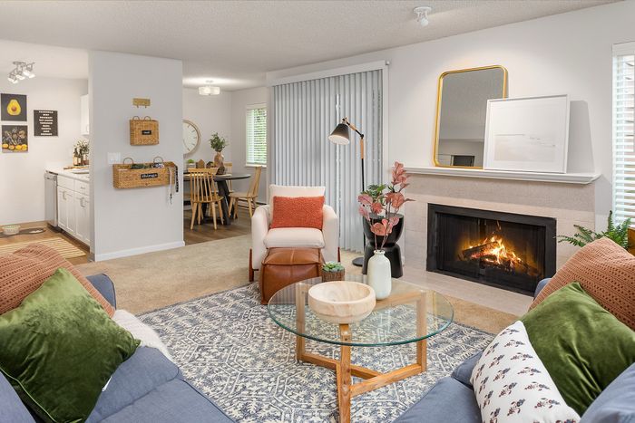 Inviting living room with cozy fireplace, stylish decor, and open layout leading to modern dining area and kitchen.