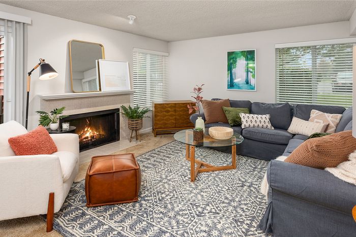 Inviting living room with modern decor, featuring a cozy fireplace, stylish furniture, and ample natural light.
