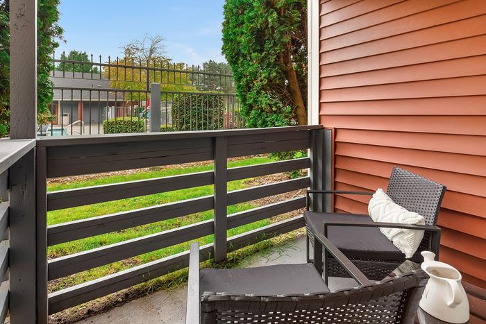 Cozy apartment patio with modern outdoor seating and lush greenery, perfect for relaxation and enjoying the view.