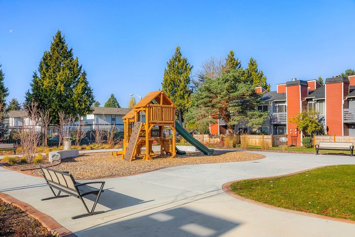 Inviting playground surrounded by vibrant apartment buildings and lush greenery, perfect for family-friendly living.