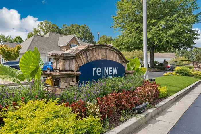 Inviting entrance to reNEW showcasing beautiful landscaping with stone details and vibrant greenery.