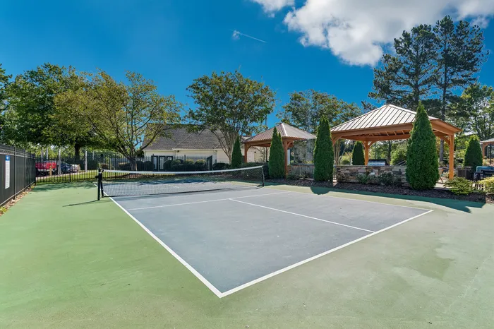 Inviting outdoor tennis court nestled among lush greenery, featuring elegant gazebos for relaxation.