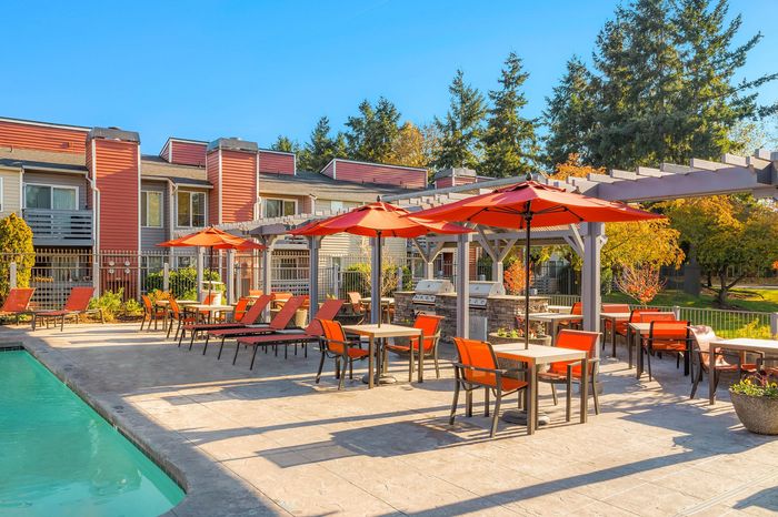 Inviting outdoor patio with vibrant orange umbrellas, comfortable seating, and a sparkling pool, perfect for relaxation and entertainment.