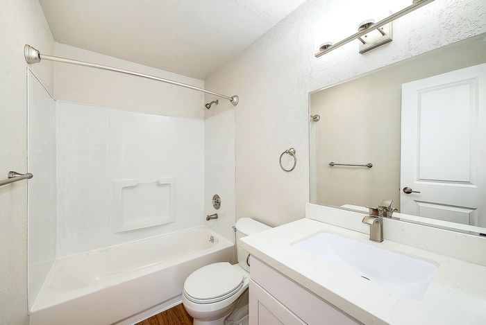 Modern bathroom featuring sleek fixtures, a spacious bathtub, and a pristine white vanity for a luxurious feel.