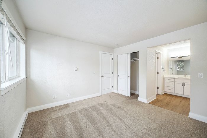 Bright, carpeted bedroom with a built-in closet and modern en-suite bathroom.