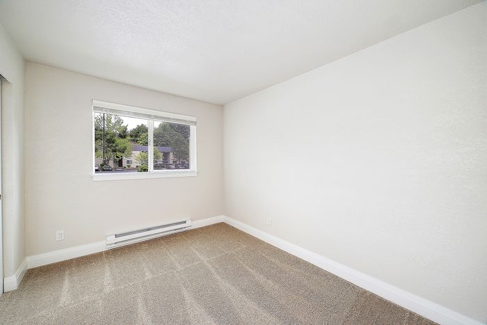 Bright bedroom with plush carpeting and a large window offering scenic views.