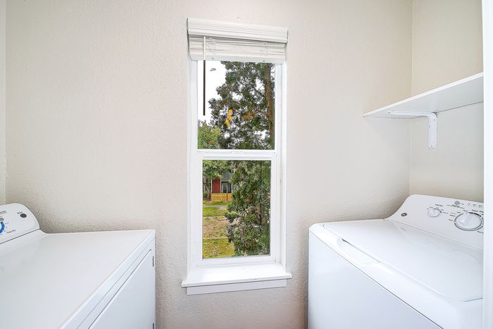 Bright laundry room with modern washer and dryer, featuring a large window with a scenic view, creating a fresh and inviting atmosphere.