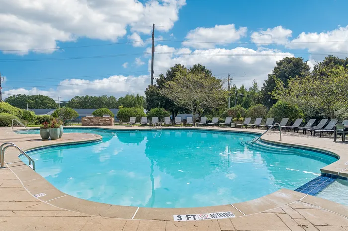 Inviting outdoor pool area with lush greenery, perfect for relaxation and sunbathing.