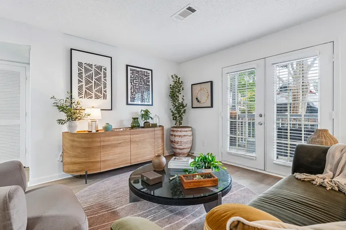 Chic and modern living room with stylish decor, indoor plants, and natural light from large patio doors.