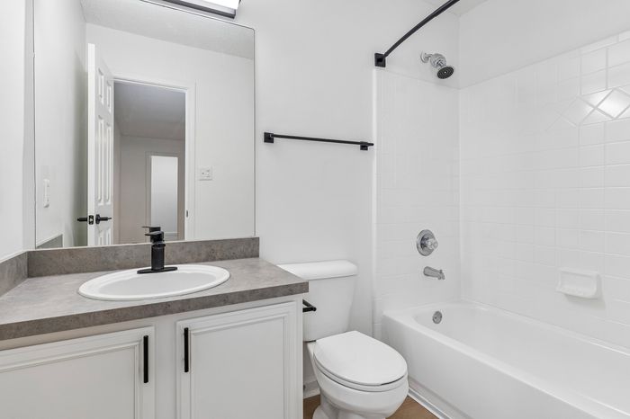 Bright, modern bathroom featuring sleek fixtures, pristine white tiles, and a stylish countertop.