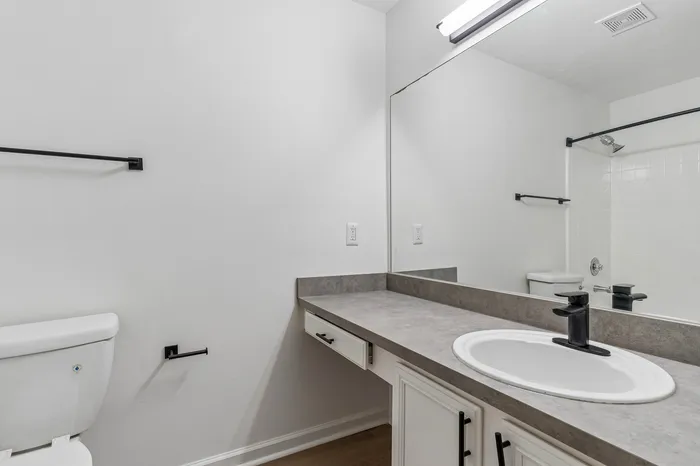 Modern bathroom with sleek countertops, elegant fixtures, and a large mirror providing a spacious feel.