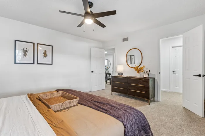 Inviting bedroom with elegant decor, featuring a cozy bed, stylish dresser, and contemporary ceiling fan.
