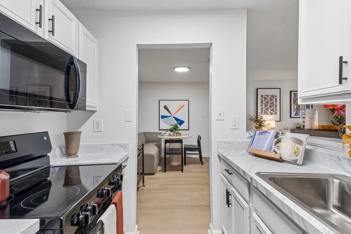 Bright kitchen with sleek appliances, marble countertops, and cozy dining nook in a modern apartment.