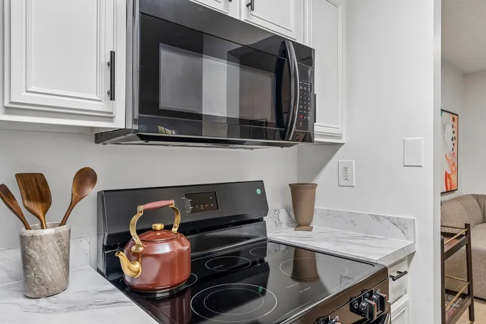 Modern kitchen setting showcasing sleek appliances, elegant marble countertops, and stylish wooden utensils for an inviting cooking space.