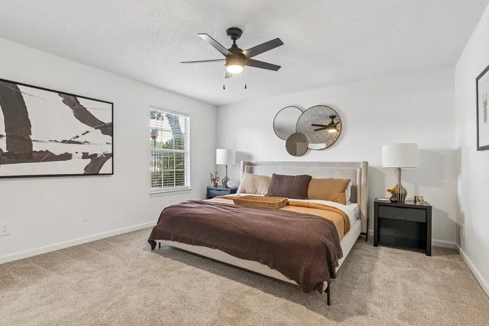Elegant bedroom featuring modern decor, plush carpeting, and a cozy bed with stylish mirrors on the wall.