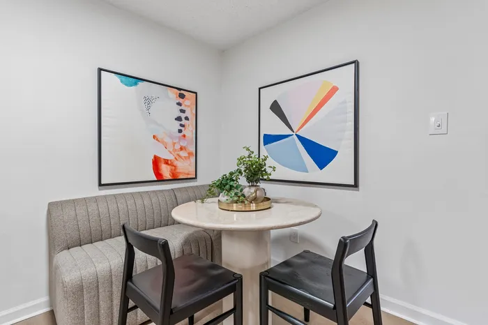 Inviting dining nook with elegant marble table, stylish gray bench, and modern artistic decor.