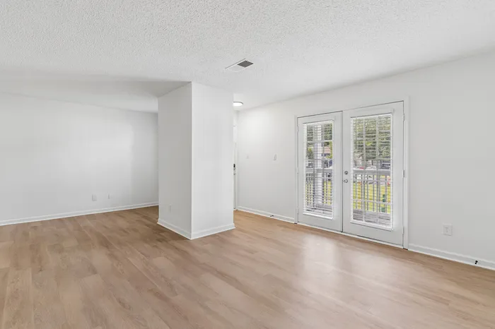 Bright and airy living space with elegant wooden flooring and French doors leading to the balcony.
