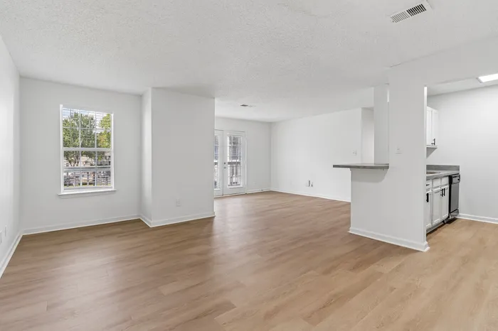 Bright and spacious open-concept living area with elegant wood flooring, ample natural light, and a modern kitchen featuring sleek countertops.