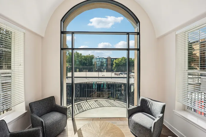 Elegant apartment room with large arch window offering a picturesque view, stylish seating, and abundant natural light.
