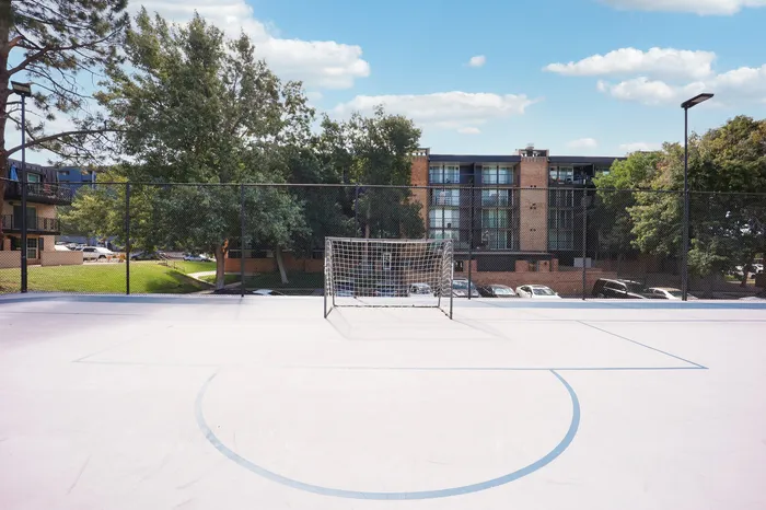 Inviting outdoor sports court with stunning apartment views, surrounded by lush green trees and clear blue skies.
