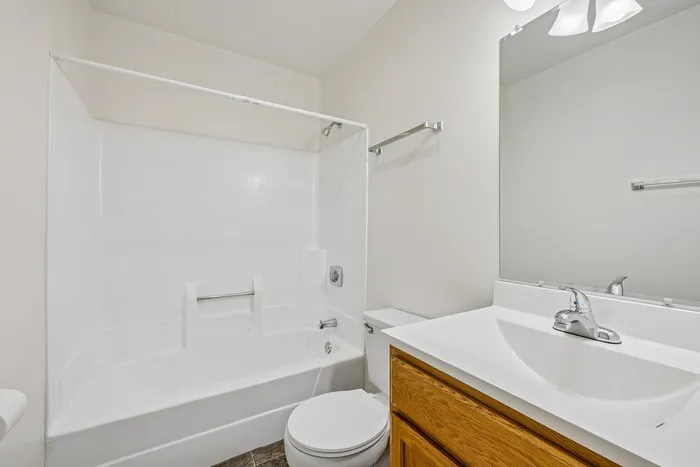 Elegant and pristine bathroom featuring a modern white bathtub, sleek vanity with ample storage, and bright lighting.