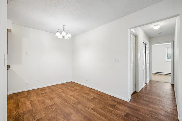 Bright dining area with elegant lighting, featuring polished wooden floors and a modern open-layout hallway.