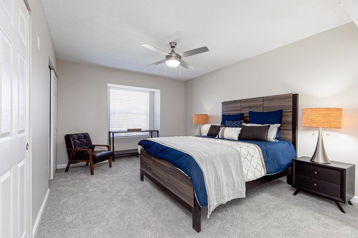 Elegant bedroom with plush carpeting, stylish modern furniture, and ambient lighting enhancing a cozy atmosphere.