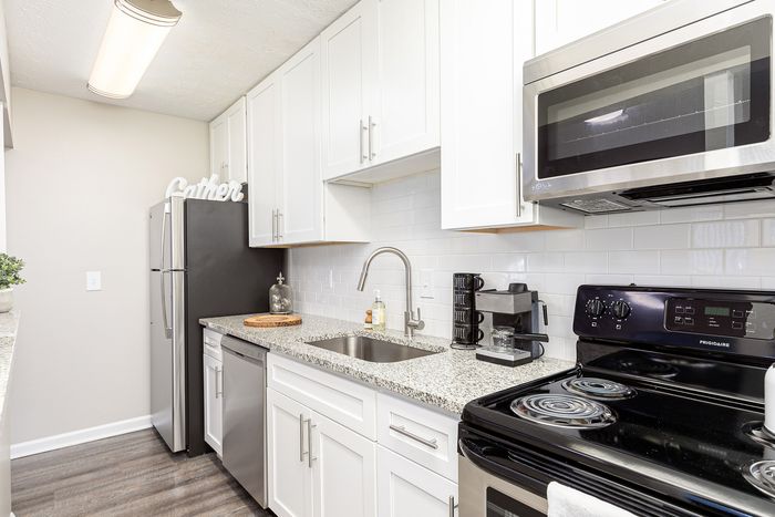 Contemporary kitchen with sleek stainless steel appliances, elegant white cabinetry, and granite countertops for a modern living experience.