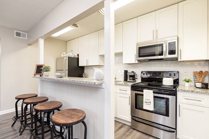 Charming modern kitchen with sleek stainless steel appliances, elegant granite countertops, and a cozy breakfast bar with stylish wooden stools.