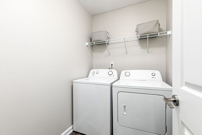 Efficient laundry room with modern washer, dryer, and stylish shelving in a bright, contemporary space.