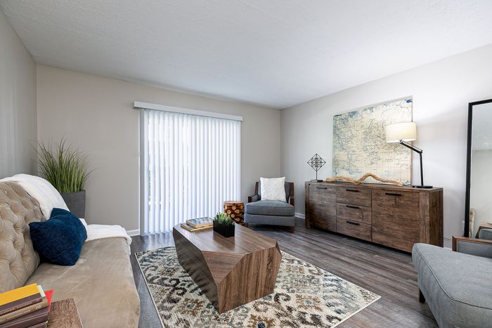 Inviting living room with modern wooden furniture, plush seating, and natural light streaming through sliding glass doors, perfect for relaxation.