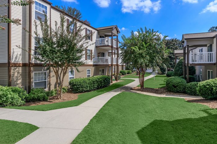Charming apartment exterior with lush greenery, inviting walkways, and balconies perfect for relaxation.