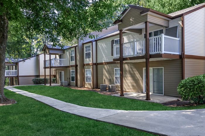 Charming apartment complex with balconies overlooking a lush green lawn, ideal for relaxed living.