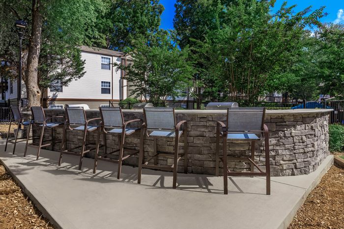Charming outdoor communal area with stylish bar stools and stone bar, ideal for gatherings and relaxation.