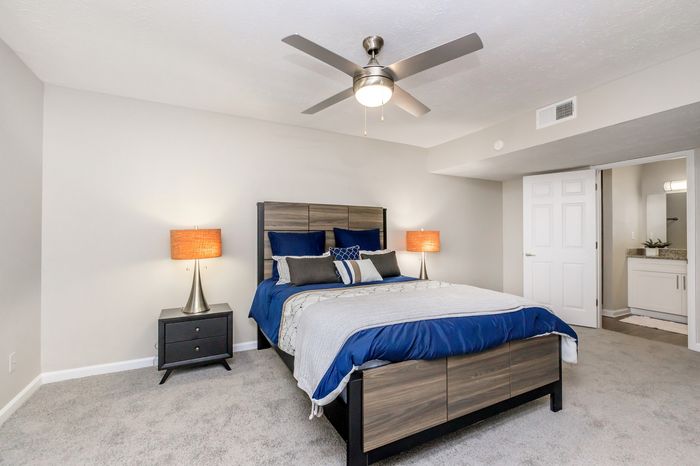 Chic bedroom with stylish decor featuring a plush double bed, modern ceiling fan, and elegant bedside lamps, leading to a pristine ensuite bathroom.