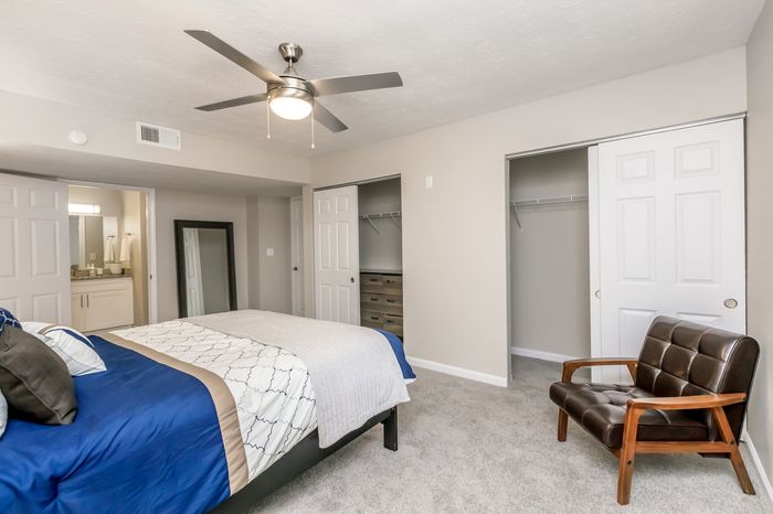 Modern bedroom with stylish decor, featuring a comfortable bed, ceiling fan, and ample closet space.