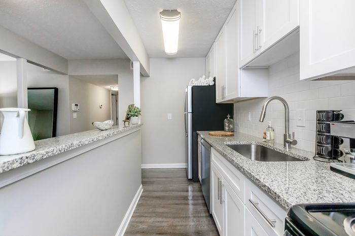 Sleek modern kitchen with granite countertops, stainless steel appliances, and chic white cabinetry.
