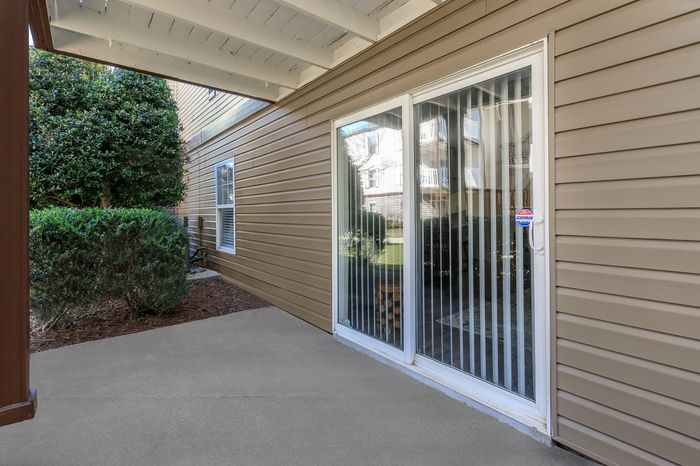 Inviting patio space with sleek sliding glass door and view of lush greenery, ideal for relaxation and outdoor enjoyment.