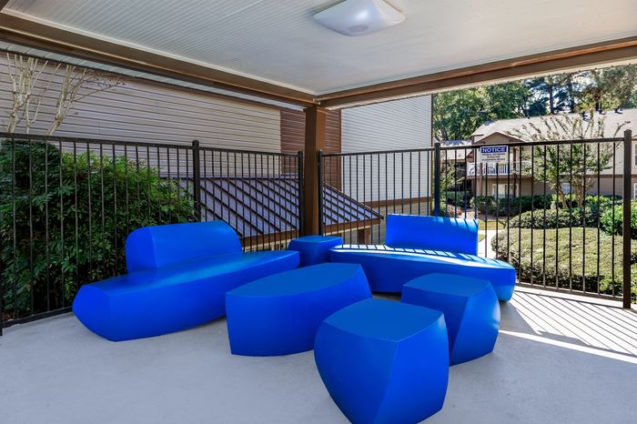 Modern outdoor lounge with vibrant blue seating, offering a stylish and comfortable gathering space with a garden view.