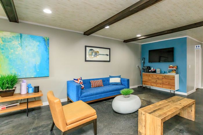 Chic modern living room featuring a vibrant blue sofa, stylish artwork, and a welcoming entertainment area.
